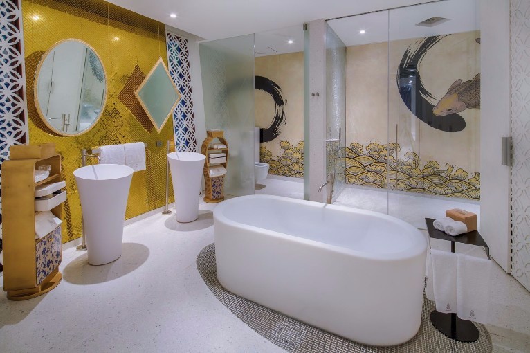 Colourful bathroom with very intricate decorative features and separate bath and shower rooms.