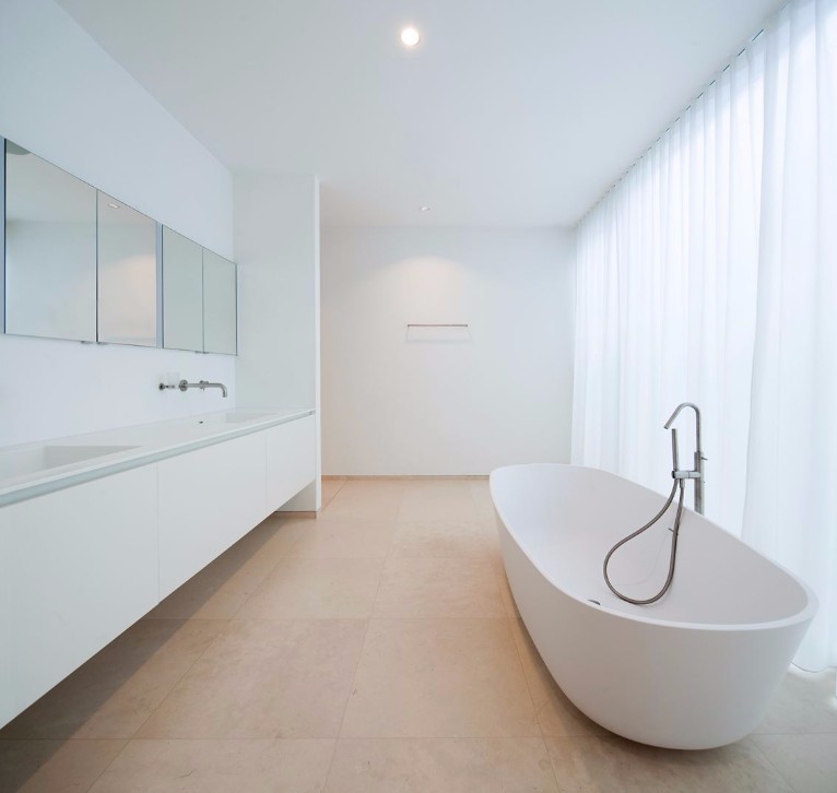 Very white, very minimalist German bathroom with clean lines and large bath.