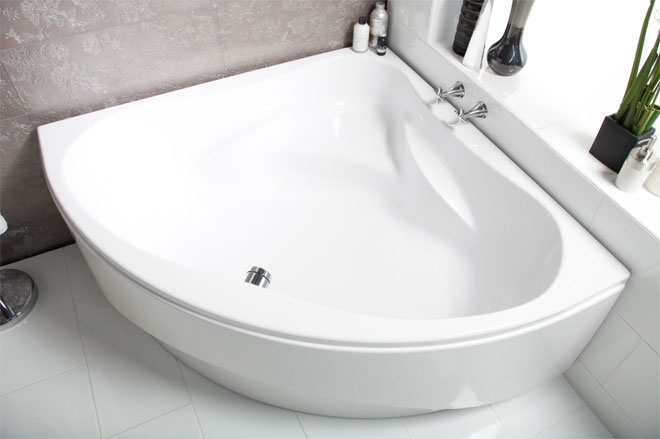 A white corner bath in a modern and stylish small bathroom.