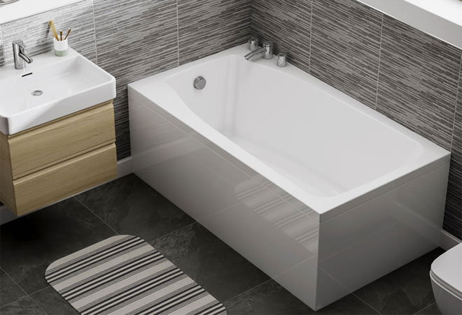 A small white compact bath in the corner of a modern, monochrome bathroom.