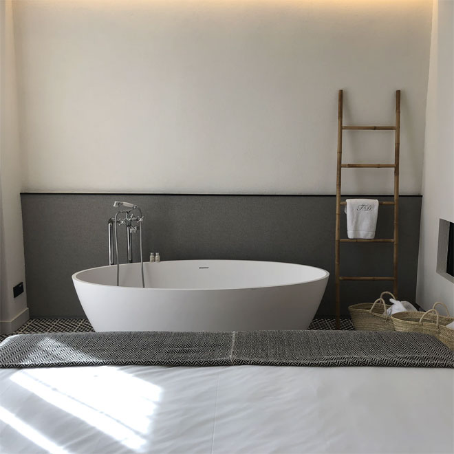 A wooden ladder leaning against a wall with a towel hanging on it in a bathroom.