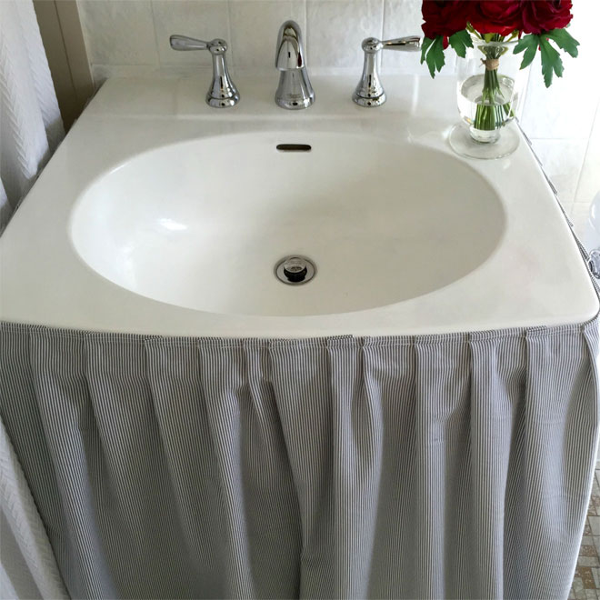 A piece of material hanging from a bathroom sink to disguise storage space underneath