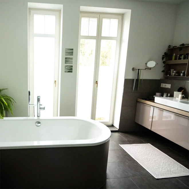 A modern bathroom with black tiled floor and freestanding bath