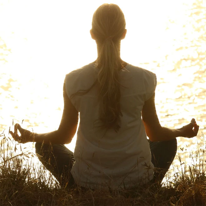 A woman meditating by water